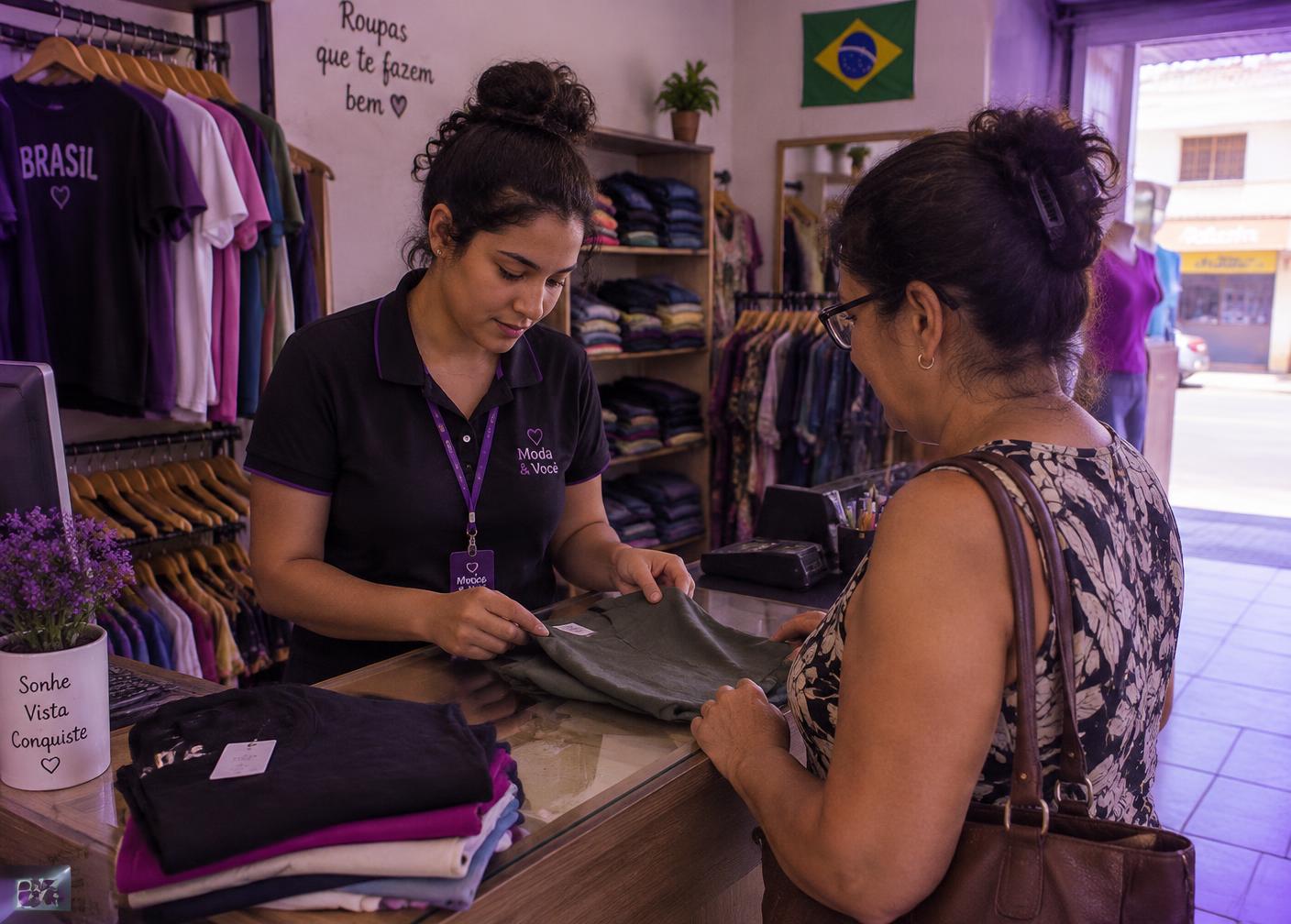 Vendedora atendendo cliente no balcão de uma loja de roupas