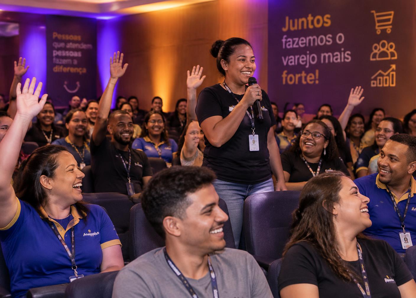 Participantes levantando a mão durante o treinamento e voluntária com microfone